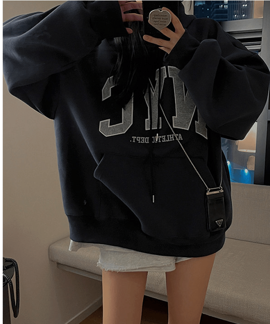 ネイビーブルーの大きめパーカーをミニワンピ風に着こなし、スマホで自撮りをする女性のアップカット。