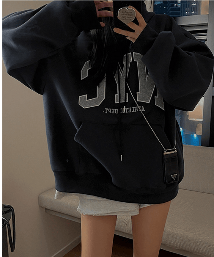 ネイビーブルーの大きめパーカーをミニワンピ風に着こなし、スマホで自撮りをする女性のアップカット。