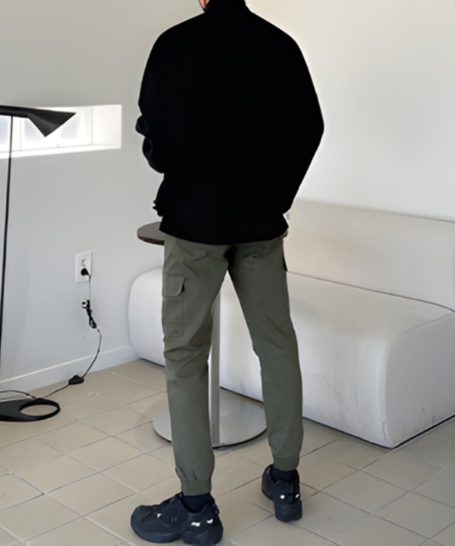ブラックのスウェットとカーキのカーゴパンツ、黒のスニーカーを合わせた、スタイリッシュなメンズのバックプレーン（後ろ姿）カット。
