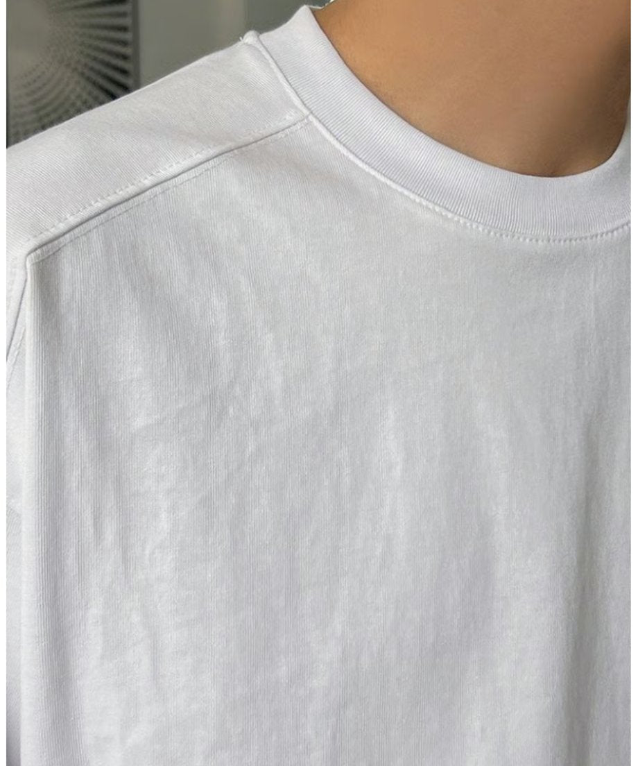 しっかりと目の詰まったクリーンなホワイトTシャツの襟元や、肩のドロップショルダーのデザインがよく分かる生地のクローズアップ。
