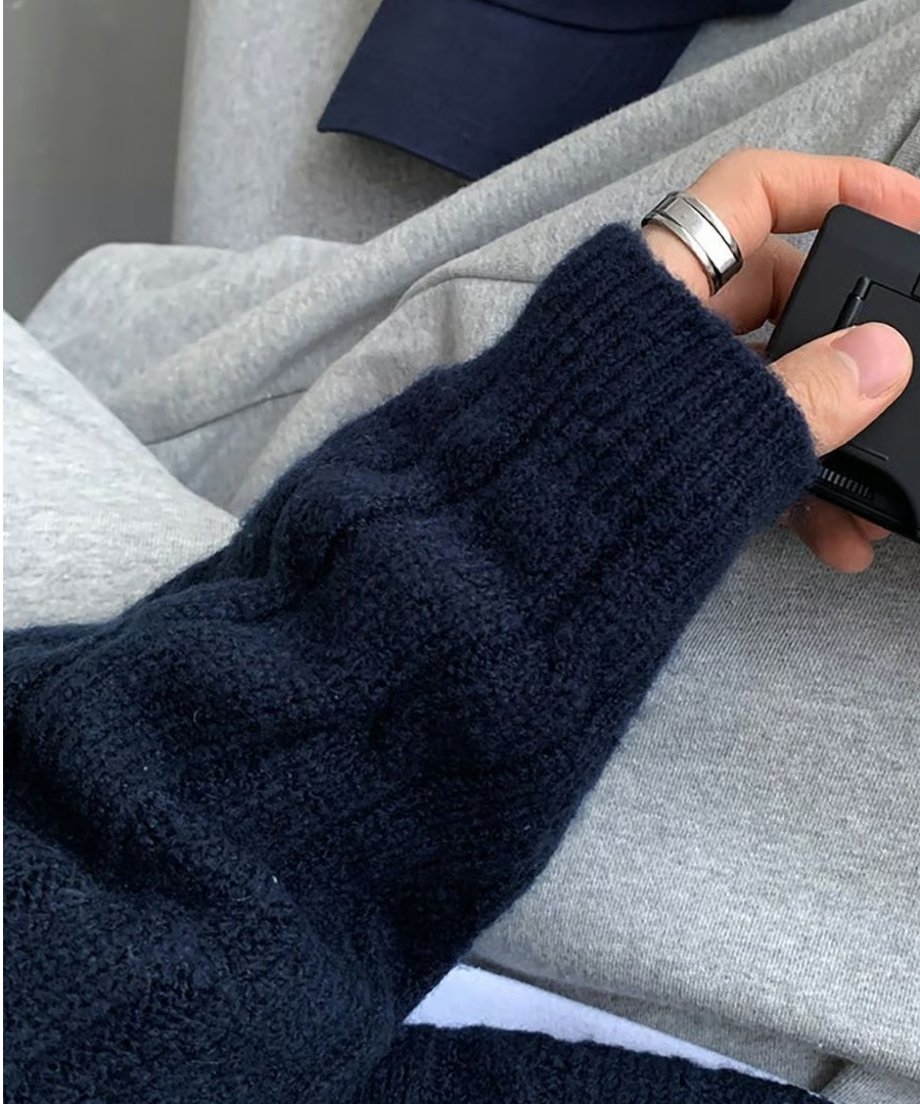 グレーのスウェットパンツに手を置き、ネイビーのケーブルニットの袖口リブとシルバーリングをはめた手元を強調したクローズアップカット。
