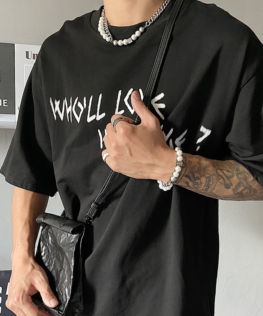 黒のワントーンストリートコーデに黒のショルダーバッグを合わせた男性のカット。胸元で輝くパールコンビネックレスと、手首に着用したお揃いのパールブレスレットが連動した洗練されたスタイリング