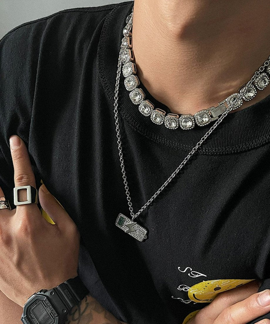 黒Tシャツにスクエアリングや黒の腕時計を合わせ、首元のビジューネックレスの輝きを際立たせたクローズアップのスタイリングカット。
