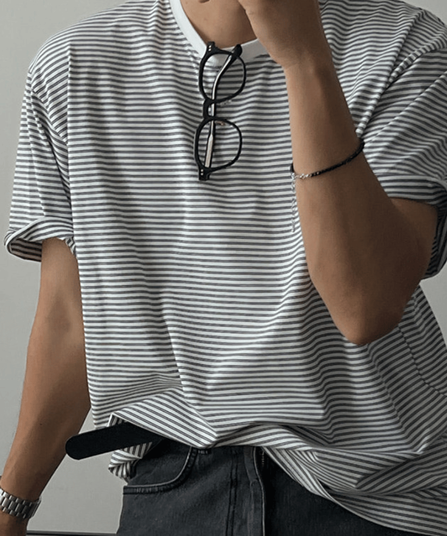 グレーのマルチストライプ柄のTシャツを着た男性が首にサングラスを掛けたショット。