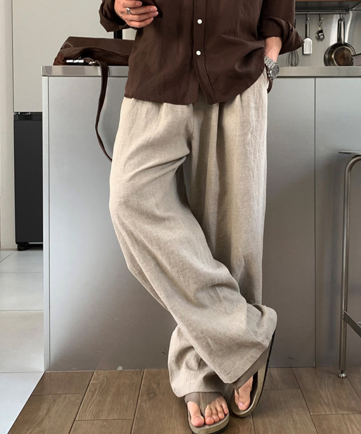 ライトカーキのプリーツワイドパンツにブラウンの長袖シャツを合わせた男性のクローズアップ写真