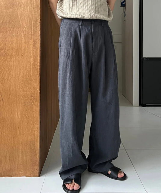 ネイビーのプリーツワイドパンツに黒のレザーサンダルを合わせた男性の足元の写真