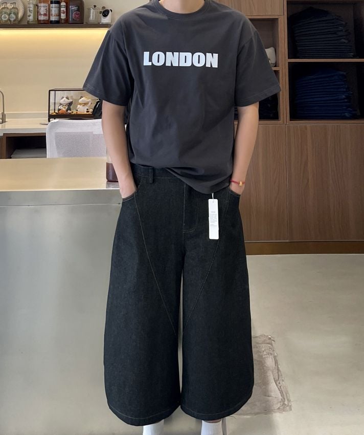 クロップドバレルレッグデニムパンツに白ソックス、チャコールグレーのTシャツを合わせた男性の正面全身姿。
