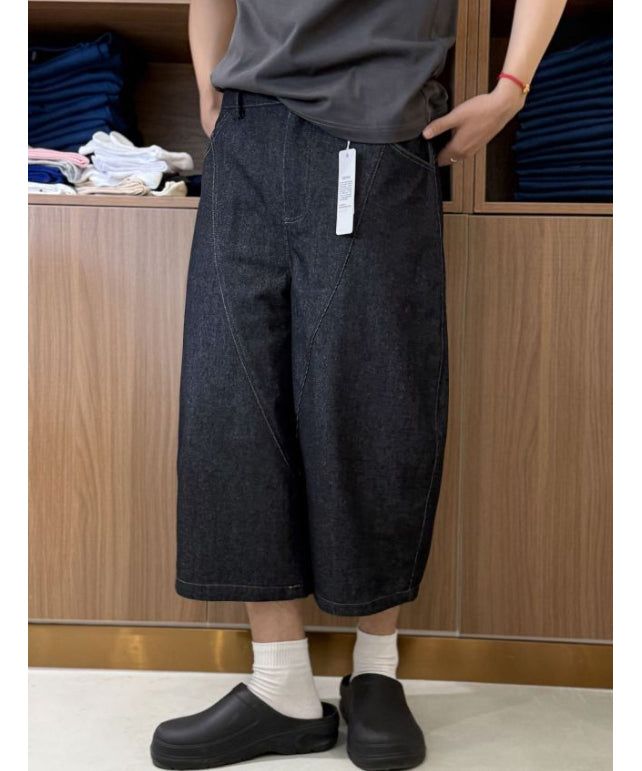クロップドバレルレッグデニムパンツを着用し、白ソックスと黒のサボサンダルを履いた男性の斜めからの足元コーディネート。