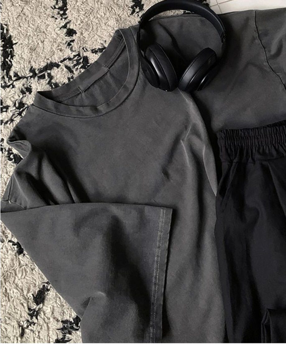 アイアングレーのTシャツの平置き画像。ヘッドホンと黒のパンツが置かれている。