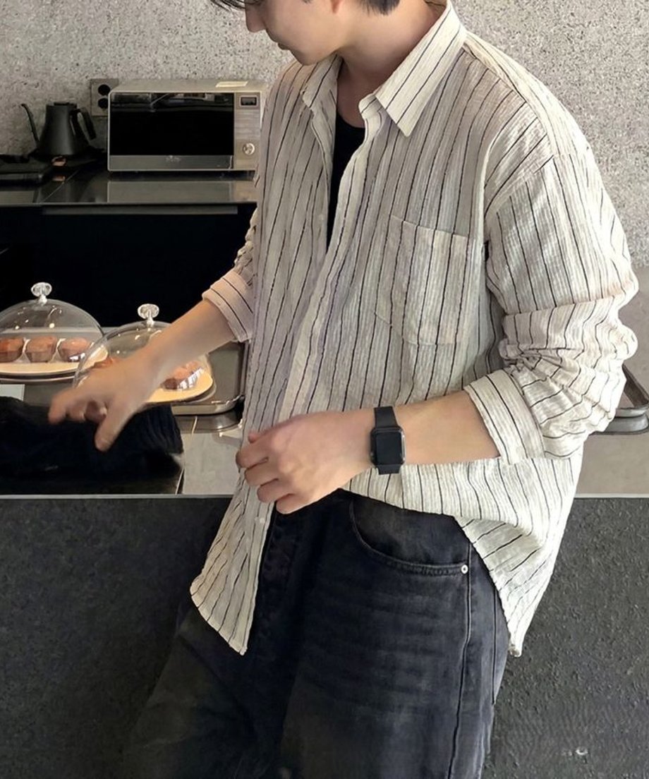 ホワイトストライプのシャツを着た男性がキッチンの前に立っているショット。