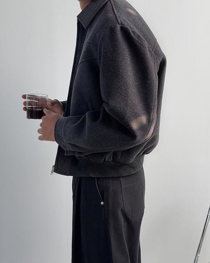 ダークグレーのスタンドカラーブルゾンを着用した男性の横姿。