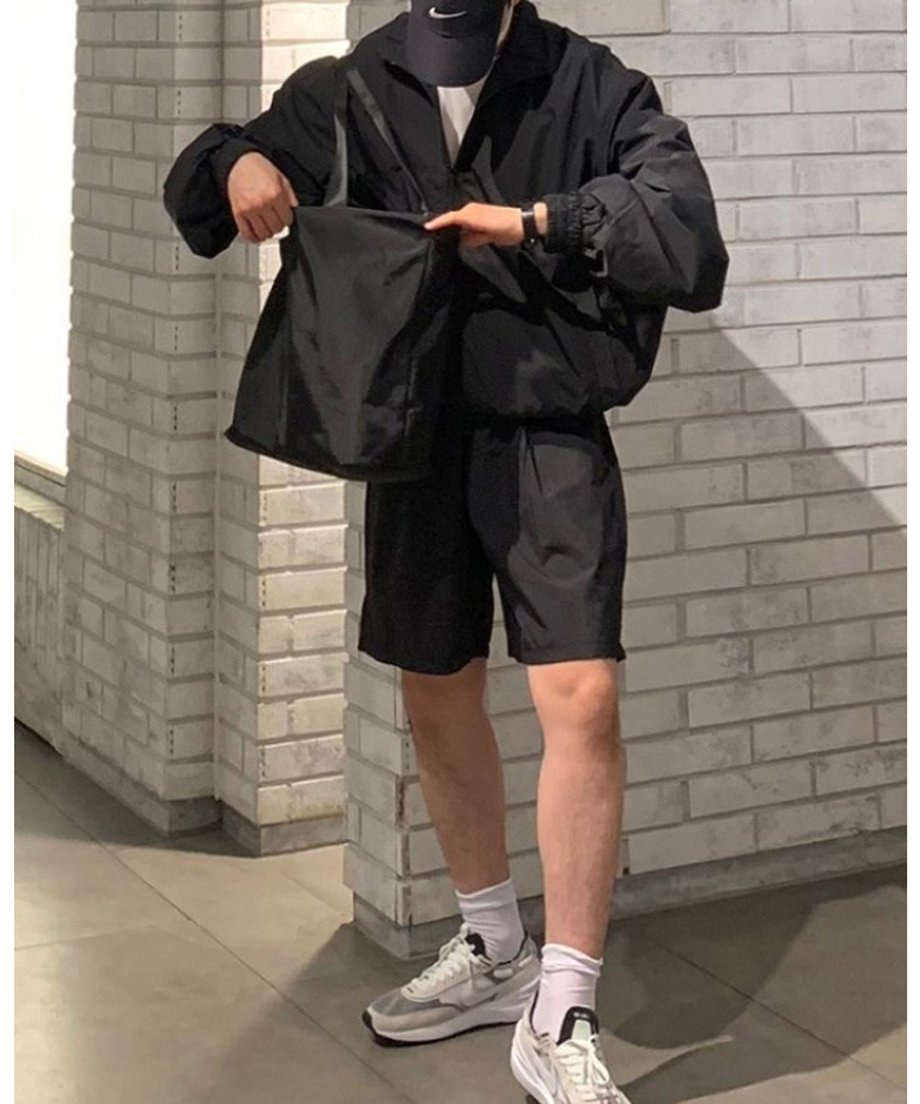 同素材の黒いナイロントートバッグを開けようとする、アクティブなストリートスポーツスタイルの男性のウエストアップ。