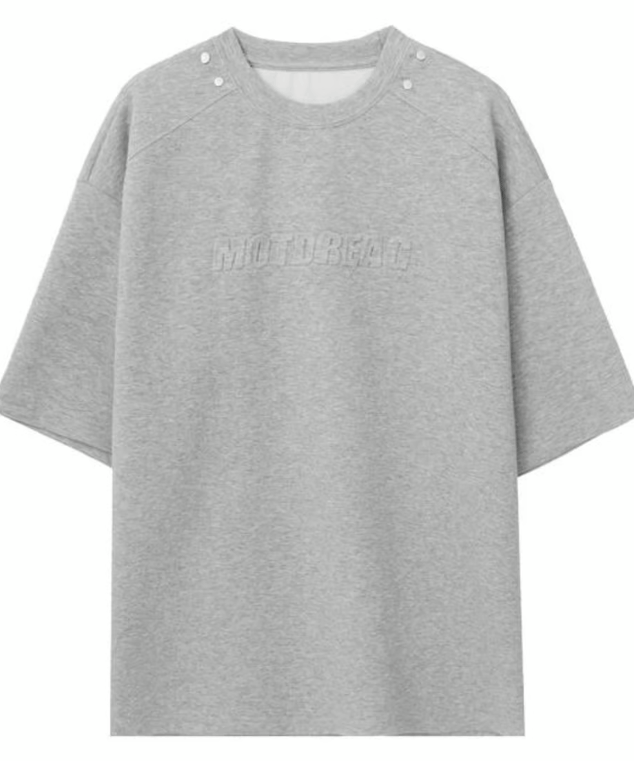 首元にスナップボタン、胸元に同色のエンボスロゴを施したグレーのセットアップのトップスの置き画フロントカット。