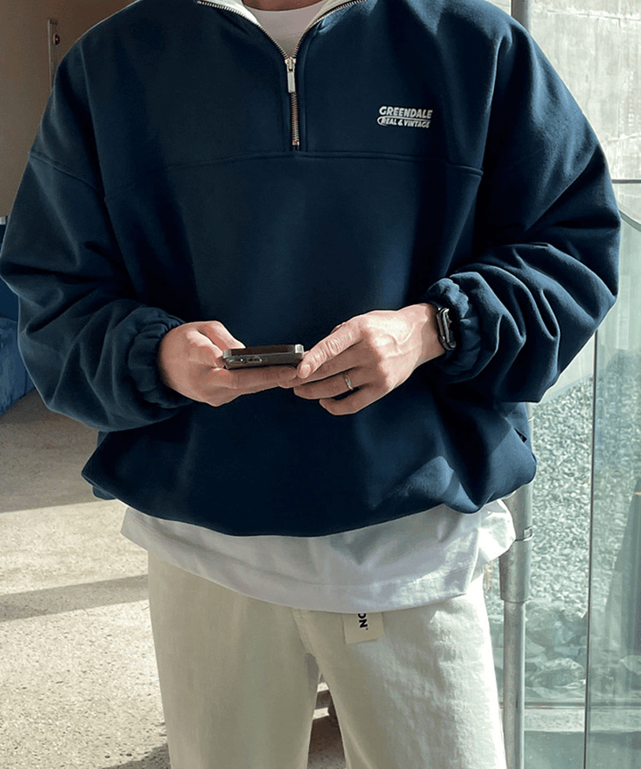 本体のネイビーブルー、内襟・インナー・パンツのホワイト、そして腕に身に着けたスマートウォッチのブラックが、手元のスマートフォンのゴールドと美しいコントラストを織りなすディテールカット。