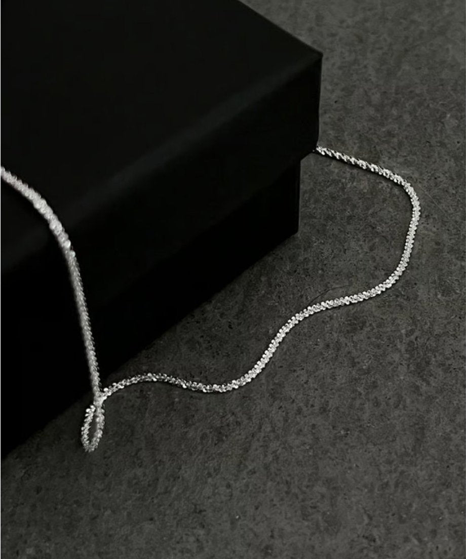 高級感のあるマットブラックのギフトボックスに添えられたネックレス。ミニマルで洗練された佇まいが、モードなブランドの世界観やギフトとしての魅力を引き立てる置き撮り画像。
