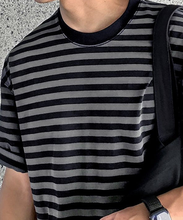 ボーダーTシャツの首元から胸元、手元までを斜めから捉えたアップカット。黒いスマートウォッチと指先のシンプルなシルバーリングが、フェード感のあるボーダー柄に映えるスタイル。