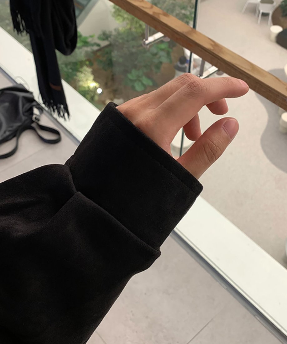 ブラックのブルゾンの袖口にフォーカスしたディテールカット。モールの吹き抜けを背景に、上品な光沢を放つ黒いフェイクスエードの贅沢な質感を表現した1枚。