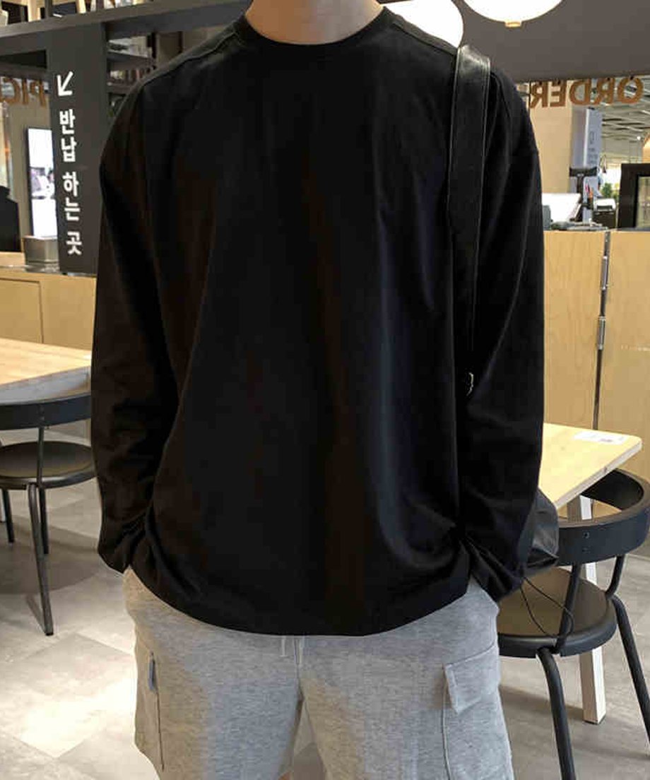 ブラックのロンTにグレーのスウェットカーゴショーツを合わせた男性のフロントスタイル。黒のレザーショルダーストラップを肩掛けし、シンプルながらもサイズ感で魅せるストリートスタイル