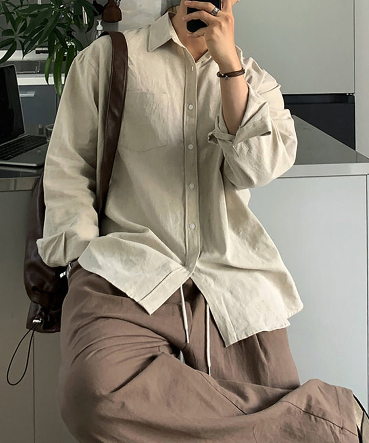 ベージュのシャツにブラウンのワイドパンツを合わせた男性のポーズカット。アースカラートーンでまとめた、大人の夏のイージーエレガンススタイル。