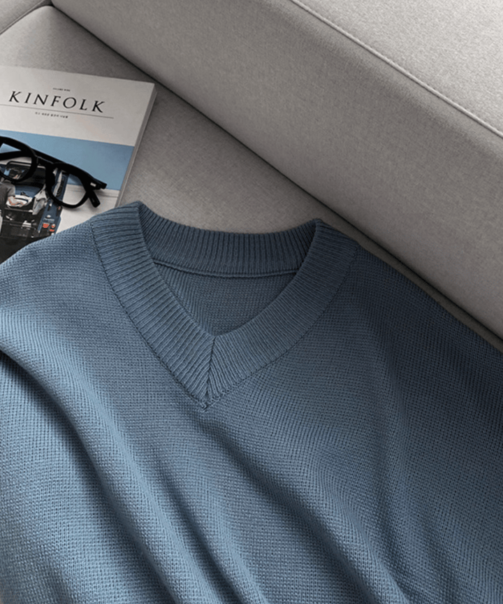 ソファーの上に無造作に置かれたライトブルーのセーター。傍らに「KINFOLK」の雑誌と黒縁メガネが添えられた、こなれ感のある物撮りカット。