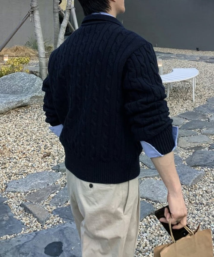 ネイビーの襟付きケーブルニットカーディガンを着用した男性のバックショット。背中全面に施された美しいケーブル編みの縦ラインと、程よいゆとりのあるシルエットが確認できる。