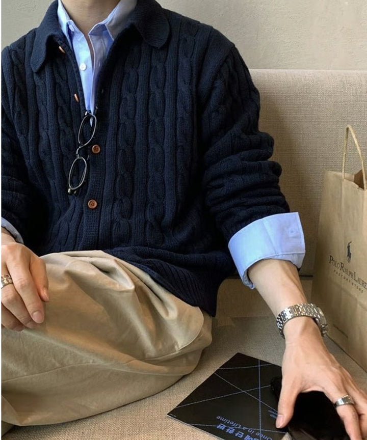 カフェのソファ席に座った男性のスタイリングカット。ネイビーのカーディガンの袖から覗くブルーのシャツのカフスやシルバーの腕時計が洗練された印象を与える。