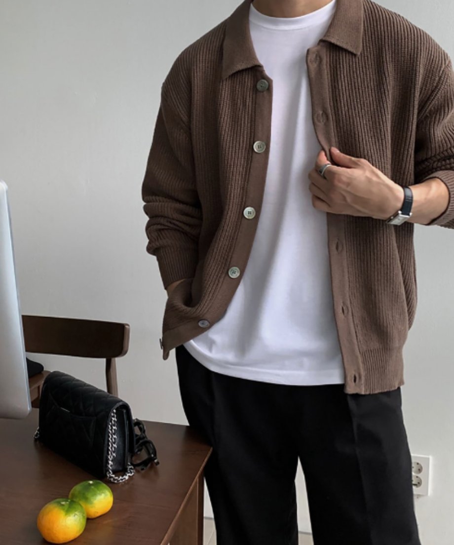 ブラウンのリブカーディガンのボタンを軽く留め、インナーの白Tシャツを見せる男性のフロントアップ。上品なマーブルボタンと、手元の黒いレザーストラップの腕時計、シルバーリングが引き立つカット。