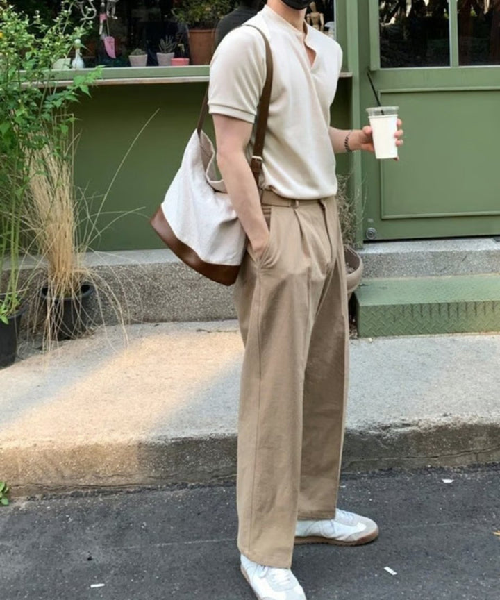 カフェのテラス席前での全身スタイリングカット。グレーのポロシャツ、ライトブラウンのレザー切り替えキャンバストートバッグ、ベージュのワイドパンツ、白スニーカーによるトータルコーディネート。