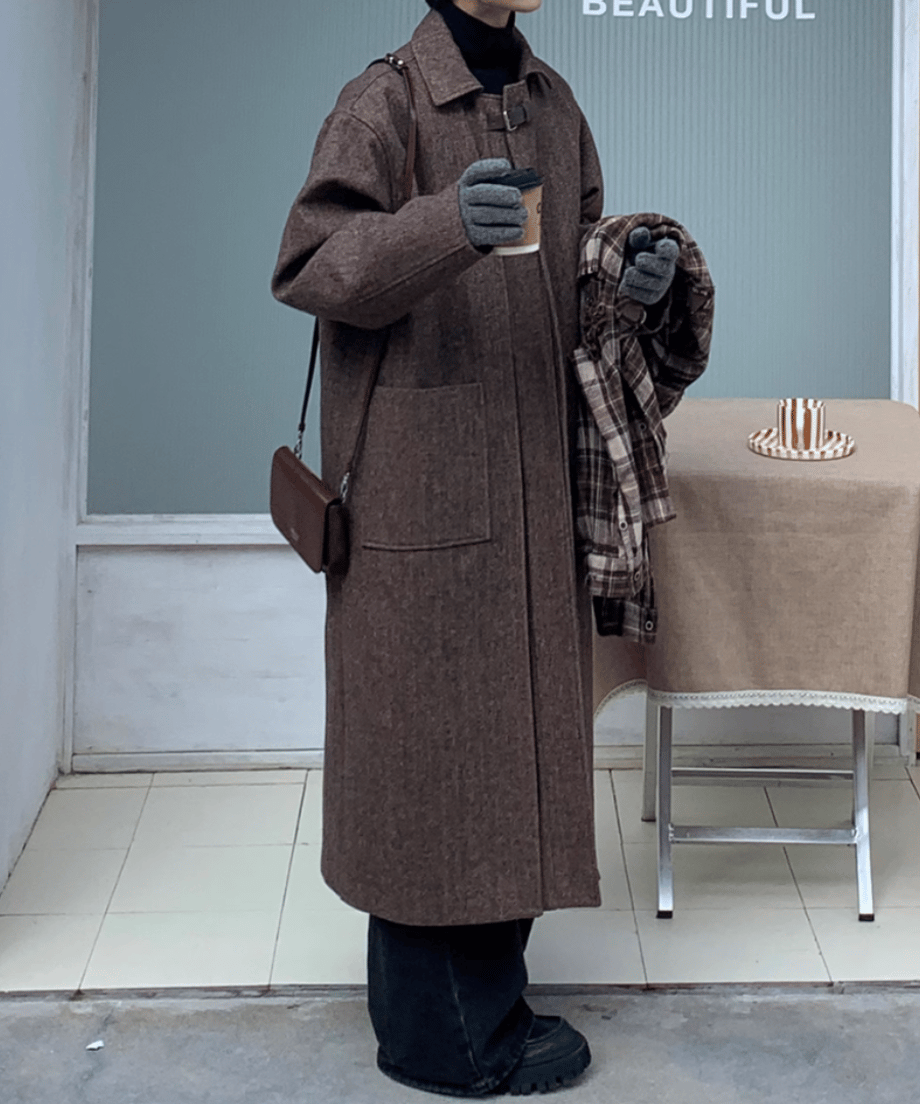 テーブルクロスの置かれたカフェのテラス席横での全身カット。モカブラウンのコート、黒のワイドパンツ、グレーの小物が調和した、洗練された冬のアーバンスタイルを提案するトータルコーディネート画像。