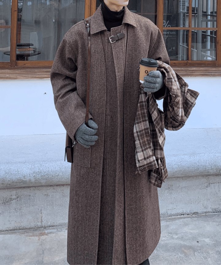正面からの上半身カット。首元のチンストラップを留め、コーヒーカップとマフラーを両手に持った佇まい。ドロップショルダーによるリラックス感と、品のある襟立ちの良さがひと目でわかる画像。