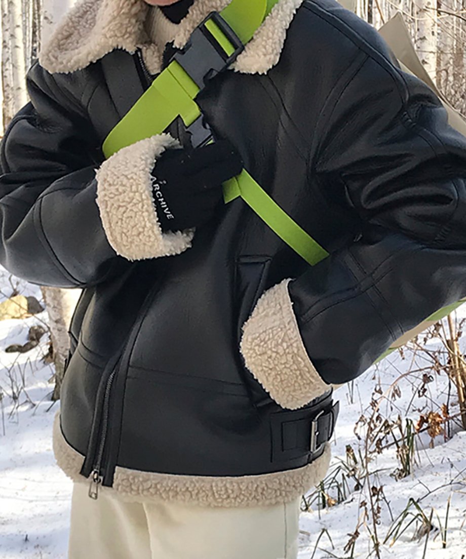 雪景色を背景に、白パンツとネオングリーンのショルダーバッグ、黒のブランドロゴグローブを合わせたアクティブなストリートスタイルのカット。