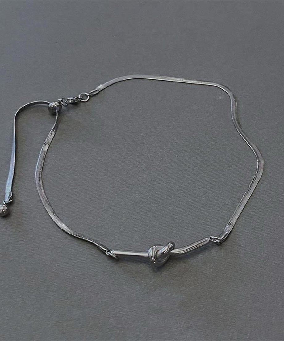 グレーの背景にフラットに置かれた商品置き画カット。ネックレス全体の構造、無段階で長さを調整できるスライダーボール付きのバックアジャスターチェーンの仕様が分かりやすい画像。