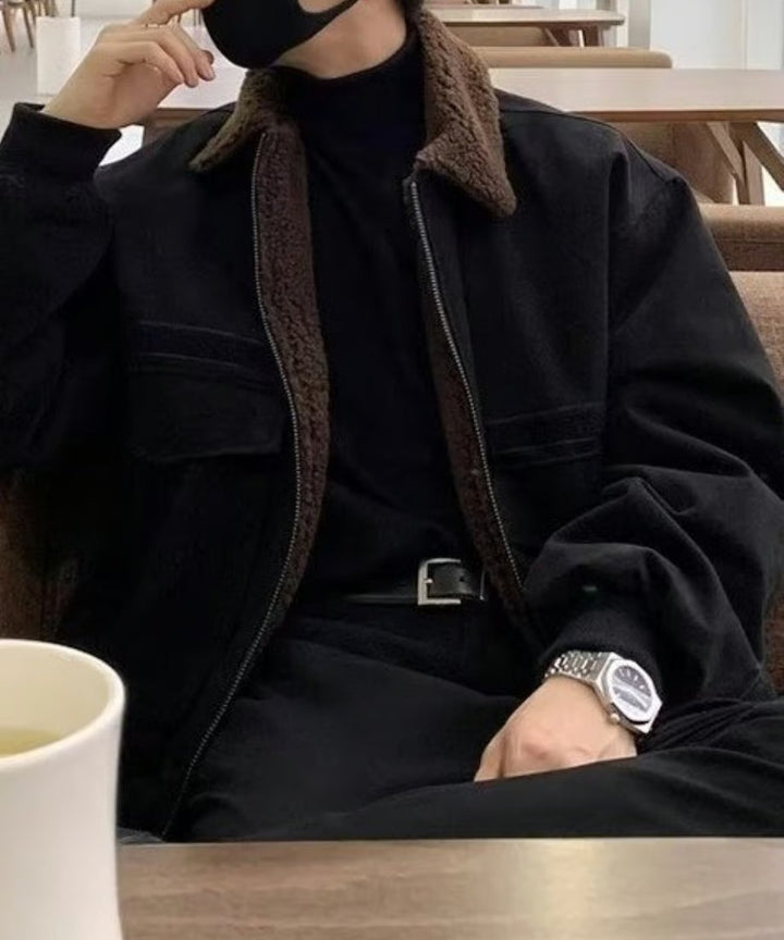 カフェのテーブル席でリラックスして座る男性の正面寄りカット。手前にマグカップを配し、ブルゾンのきめ細かな生地の質感と、タックインしたウエストまわりのスマートな着こなしにフォーカス。
