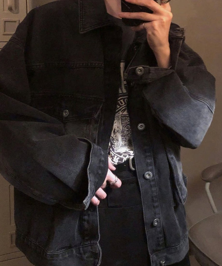 室内でスマートフォンを構える男性のウエストアップカット。フロントボタンを少し開け、インナーのTシャツを見せつつ、ゆったりとしたアームホール（袖）のルーズなサイズ感が強調された一枚。