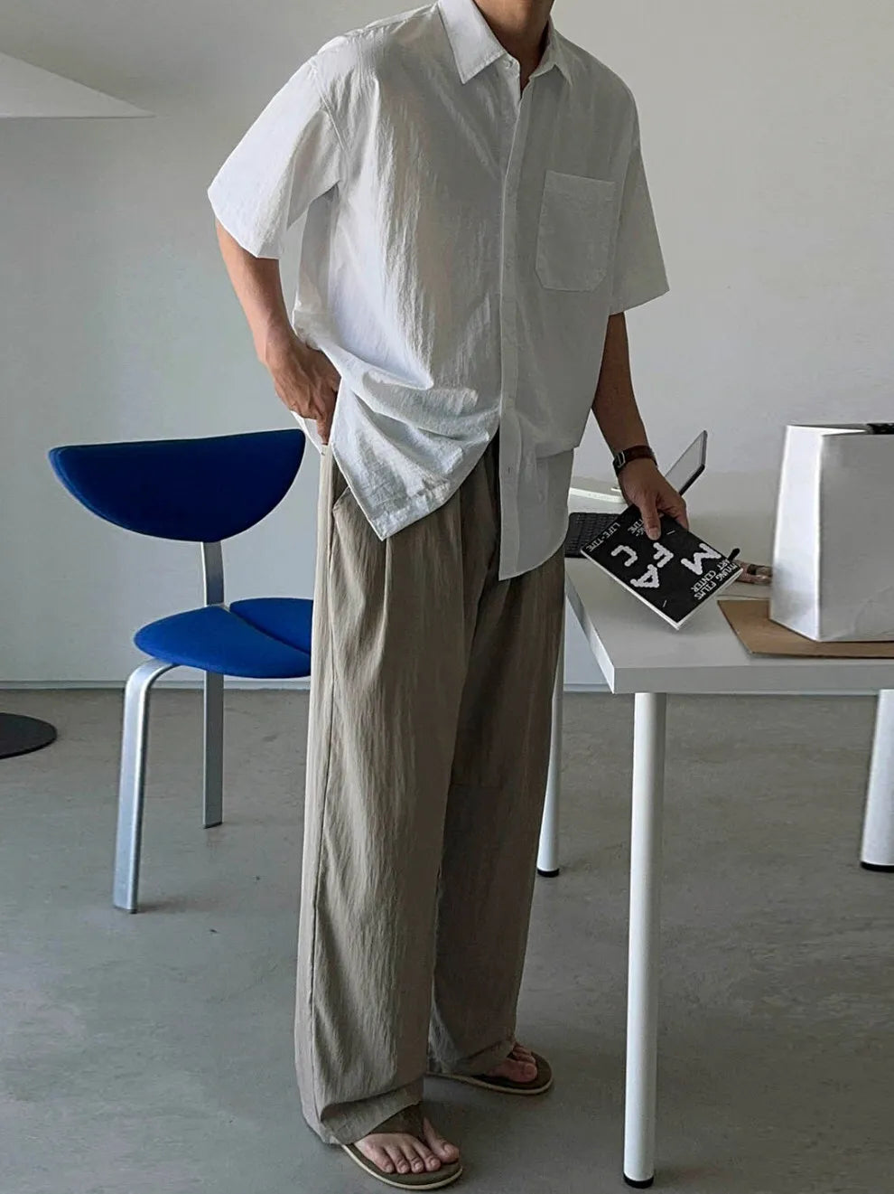 半袖シャツにカーキのゆったりとしたスラックス、レザーサンダルを合わせた男性のスタイリングカット